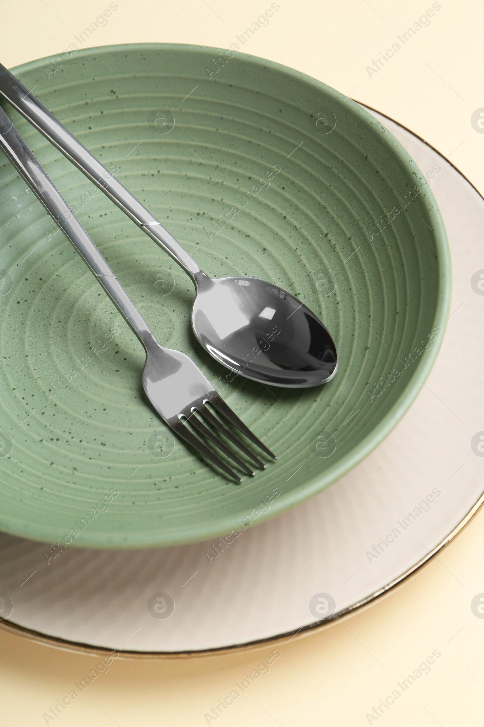 Photo of Stylish ceramic plate, bowl and cutlery on beige background