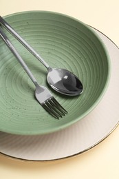 Stylish ceramic plate, bowl and cutlery on beige background