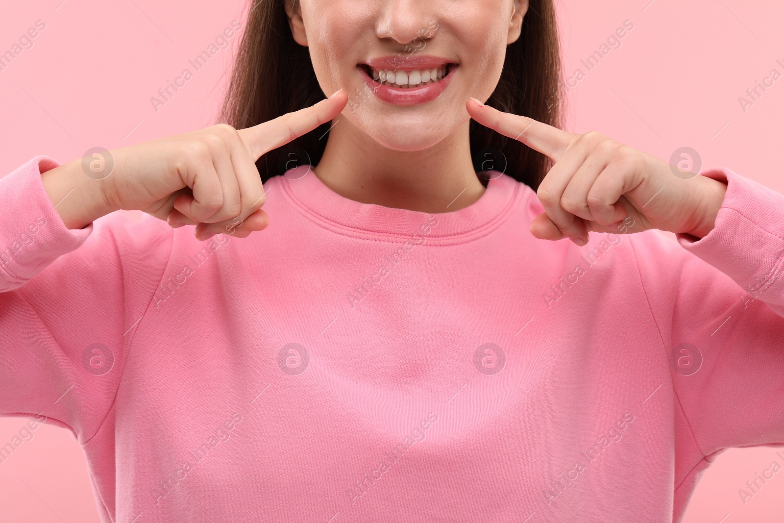 Photo of Beautiful woman showing her clean teeth and smiling on pink background, closeup