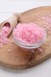 Photo of Bowl and scoop with pink sea salt on white wooden table, closeup