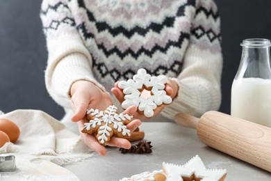 Woman holding delicious homemade Christmas cookies at grey marble table, closeup