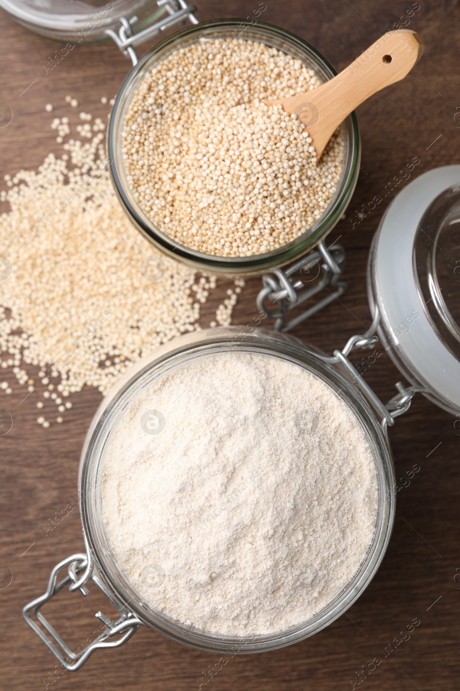 Photo of Jars with quinoa flour and seeds on wooden table, flat lay