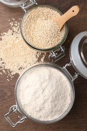 Photo of Jars with quinoa flour and seeds on wooden table, flat lay