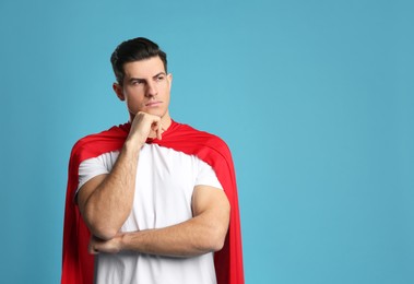 Photo of Man wearing superhero cape on light blue background. Space for text