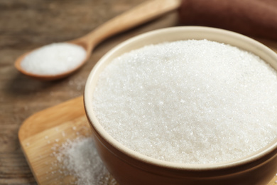 Photo of Granulated sugar in bowl on table, closeup