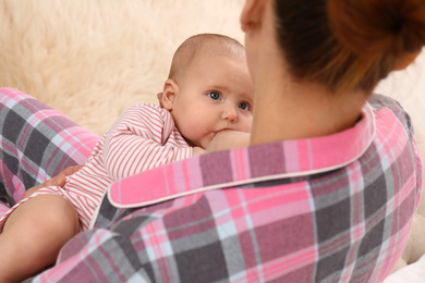 Photo of Young woman breastfeeding her little baby at home, closeup