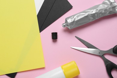 Glue, colorful paper and scissors on pink background, flat lay