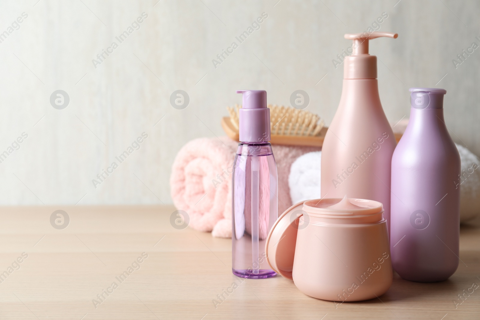 Photo of Different hair care products, towel and brush on wooden table. Space for text