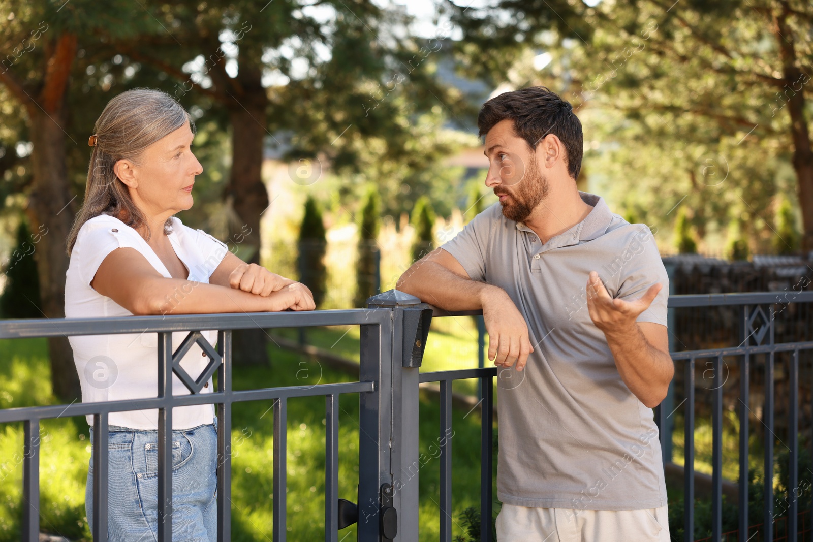 Photo of Emotional neighbours having argument near fence outdoors