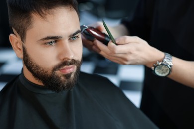 Professional hairdresser working with client in barbershop