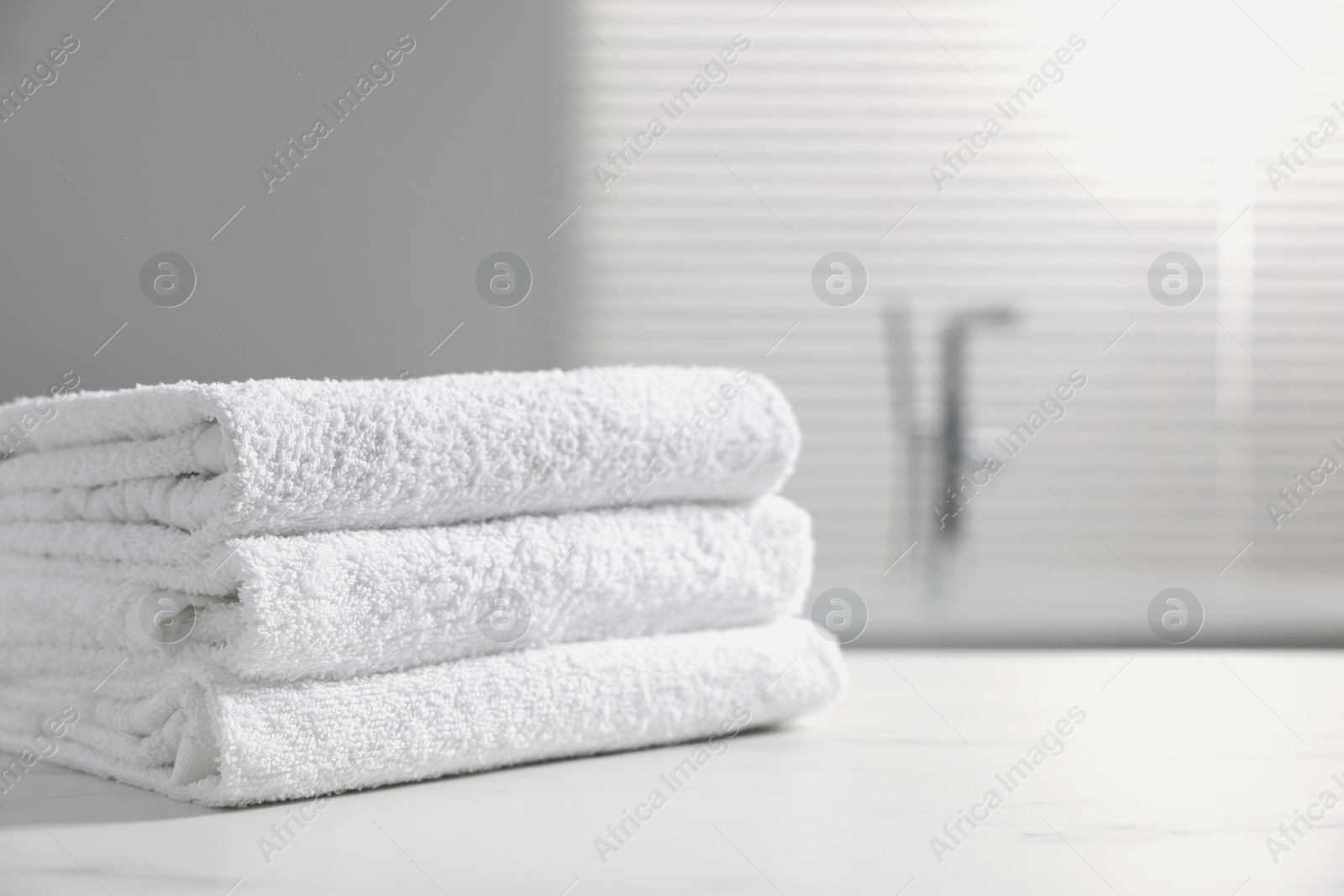 Photo of Stacked bath towels on white table indoors. Space for text