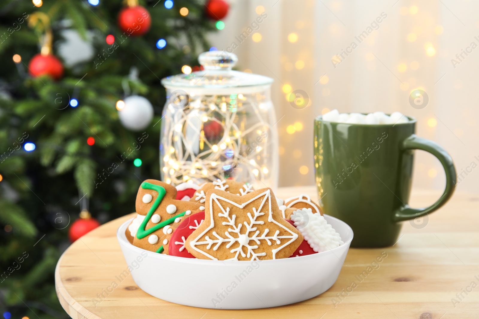 Photo of Plate with tasty homemade Christmas cookies and cup of cacao on table