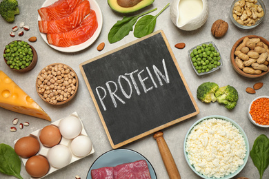 Photo of Chalkboard with word PROTEIN and different products on light table, flat lay