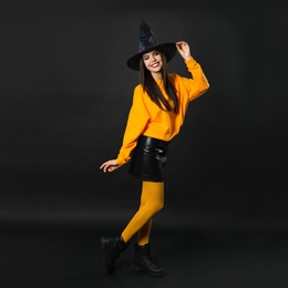 Photo of Beautiful woman wearing witch costume for Halloween party on black background