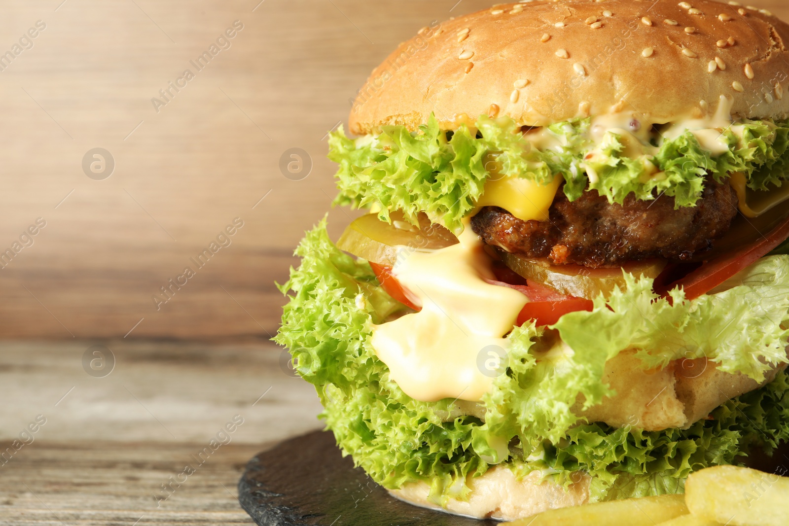 Burger with delicious patty on wooden table, closeup. Space for text Photo of Burger with delicious patty on wooden table, closeup. Space for text