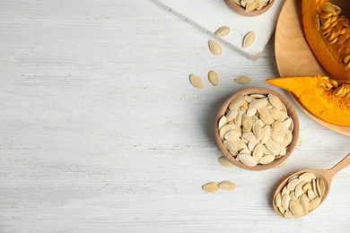 Photo of Flat lay composition with raw pumpkin seeds on white wooden table, space for text