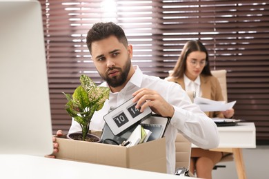 Photo of Dismissed man packing personal stuff into box in office