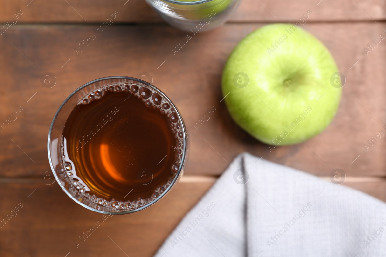Photo of Glass of fresh apple juice on wooden table, top view