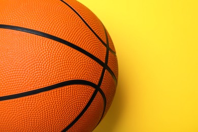 Photo of Orange ball on yellow background, top view with space for text. Basketball equipment