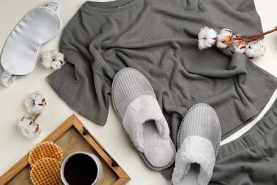 Photo of Flat lay composition with slippers and pajamas on beige background. Comfortable home outfit