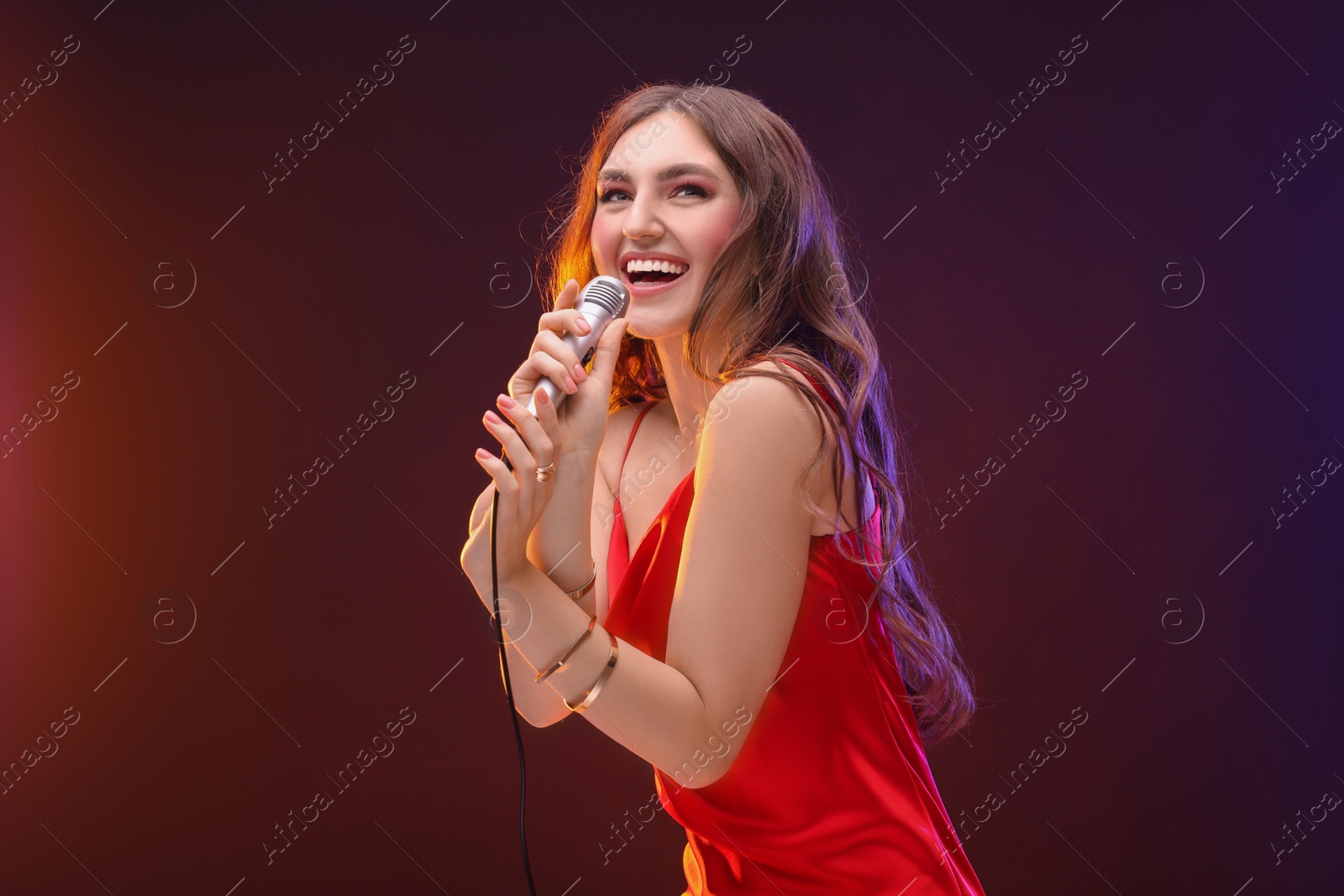 Photo of Emotional woman with microphone singing in color lights