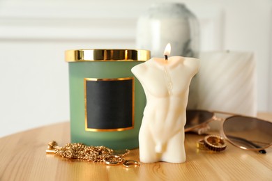 Male figure shaped candle on wooden table. Stylish decor