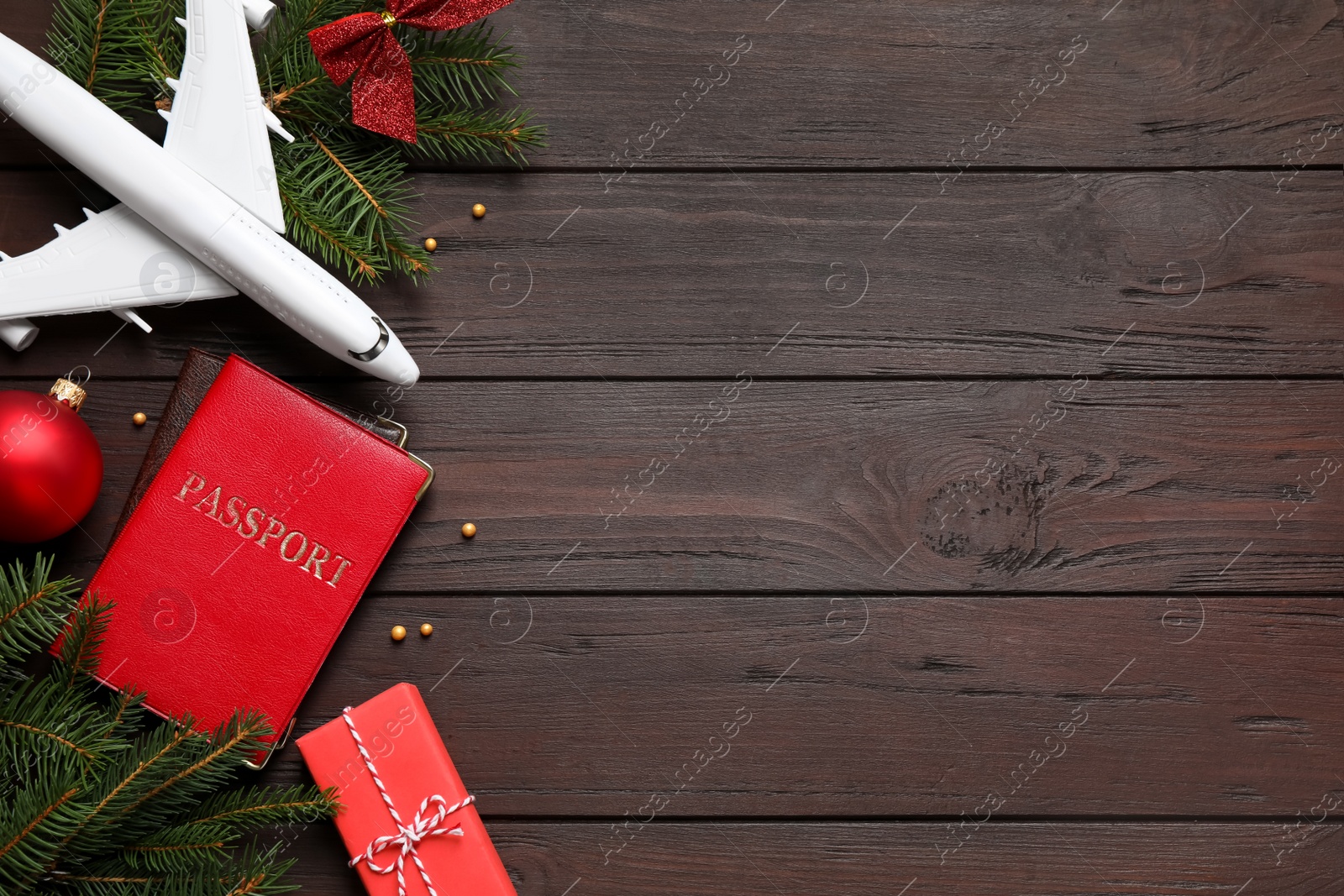 Photo of Flat lay composition with Christmas decorations and toy airplane on wooden background, space for text. Winter vacation