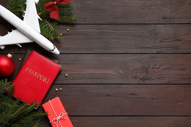 Photo of Flat lay composition with Christmas decorations and toy airplane on wooden background, space for text. Winter vacation