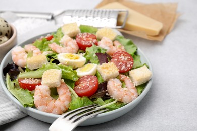 Delicious Caesar salad with shrimps and fork served on light table, closeup