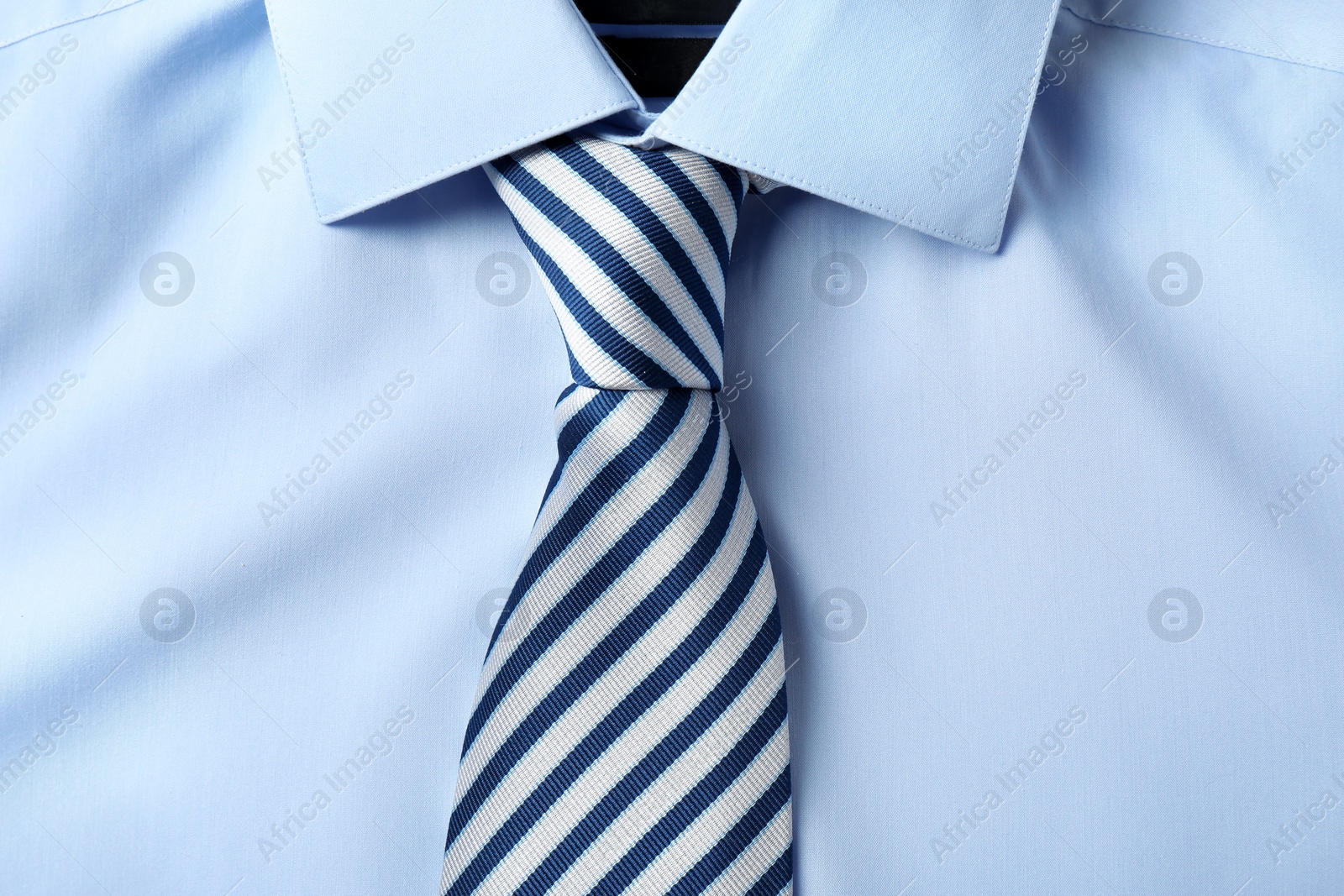 Photo of Striped male necktie on blue shirt, closeup