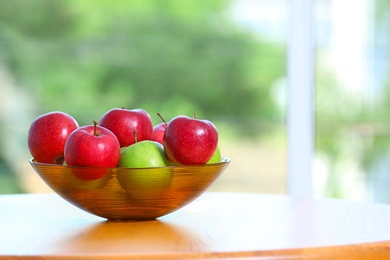 Bowl of fresh apples on table indoors. Space for text