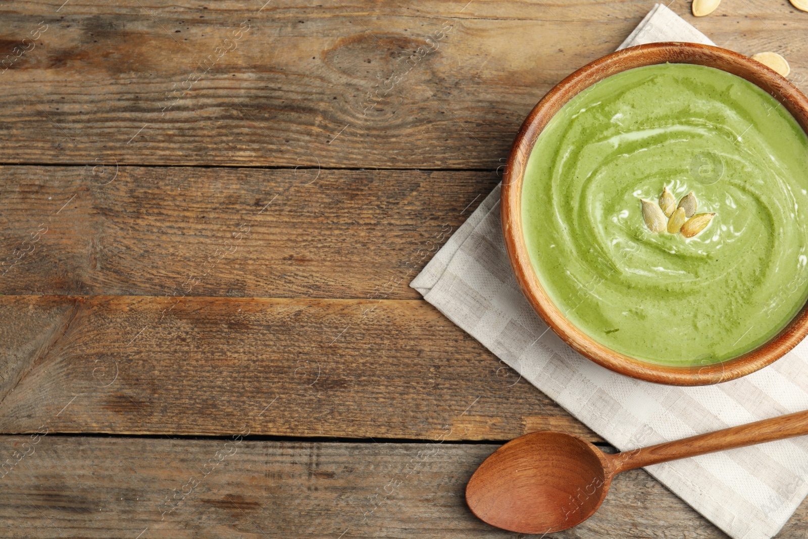 Photo of Delicious broccoli cream soup served on wooden table, flat lay. Space for text