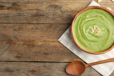 Photo of Delicious broccoli cream soup served on wooden table, flat lay. Space for text