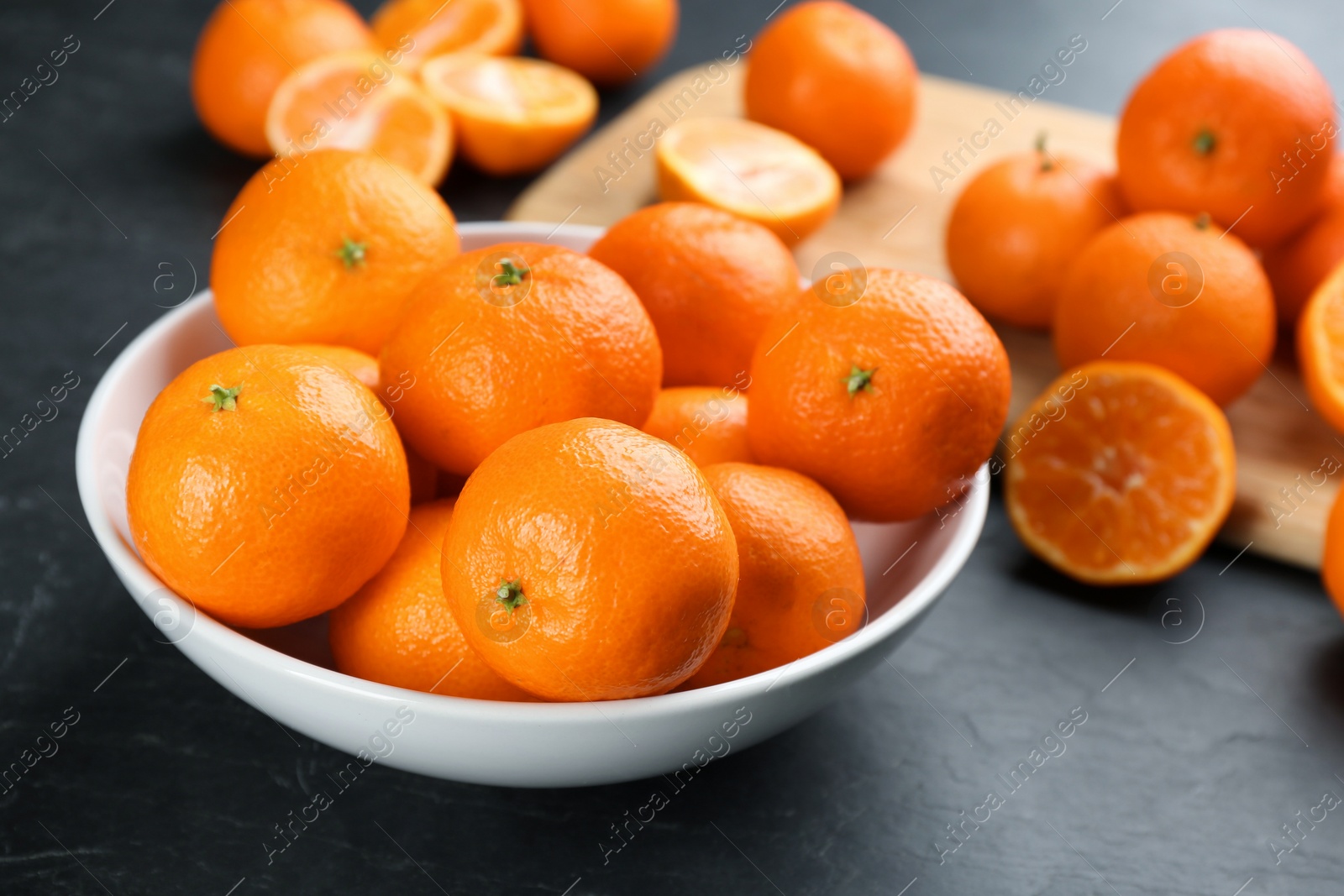 Photo of Fresh ripe tangerines on black table, closeup