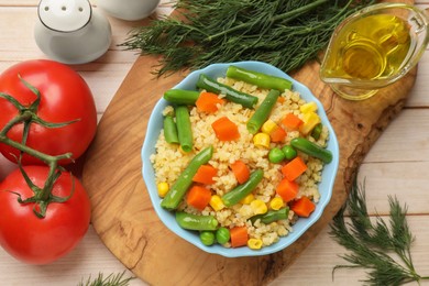 Photo of Delicious bulgur with vegetables in bowl, spices and oil on table, flat lay