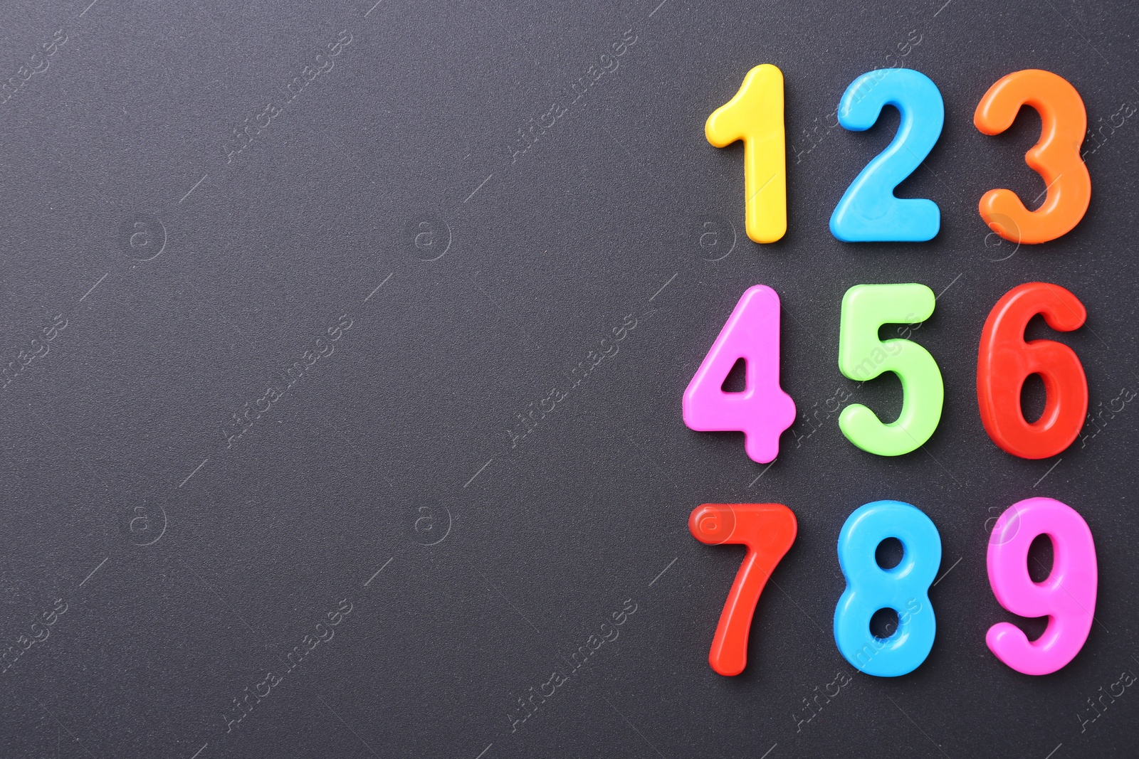 Photo of Colorful numbers on dark gray background, flat lay. Space for text