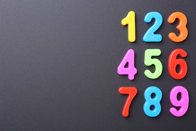 Photo of Colorful numbers on dark gray background, flat lay. Space for text