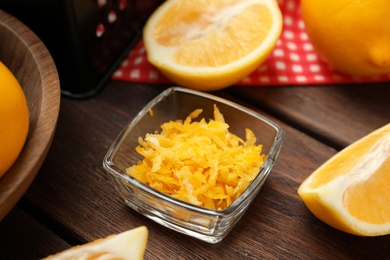 Grated lemon zest and fresh fruits on wooden table