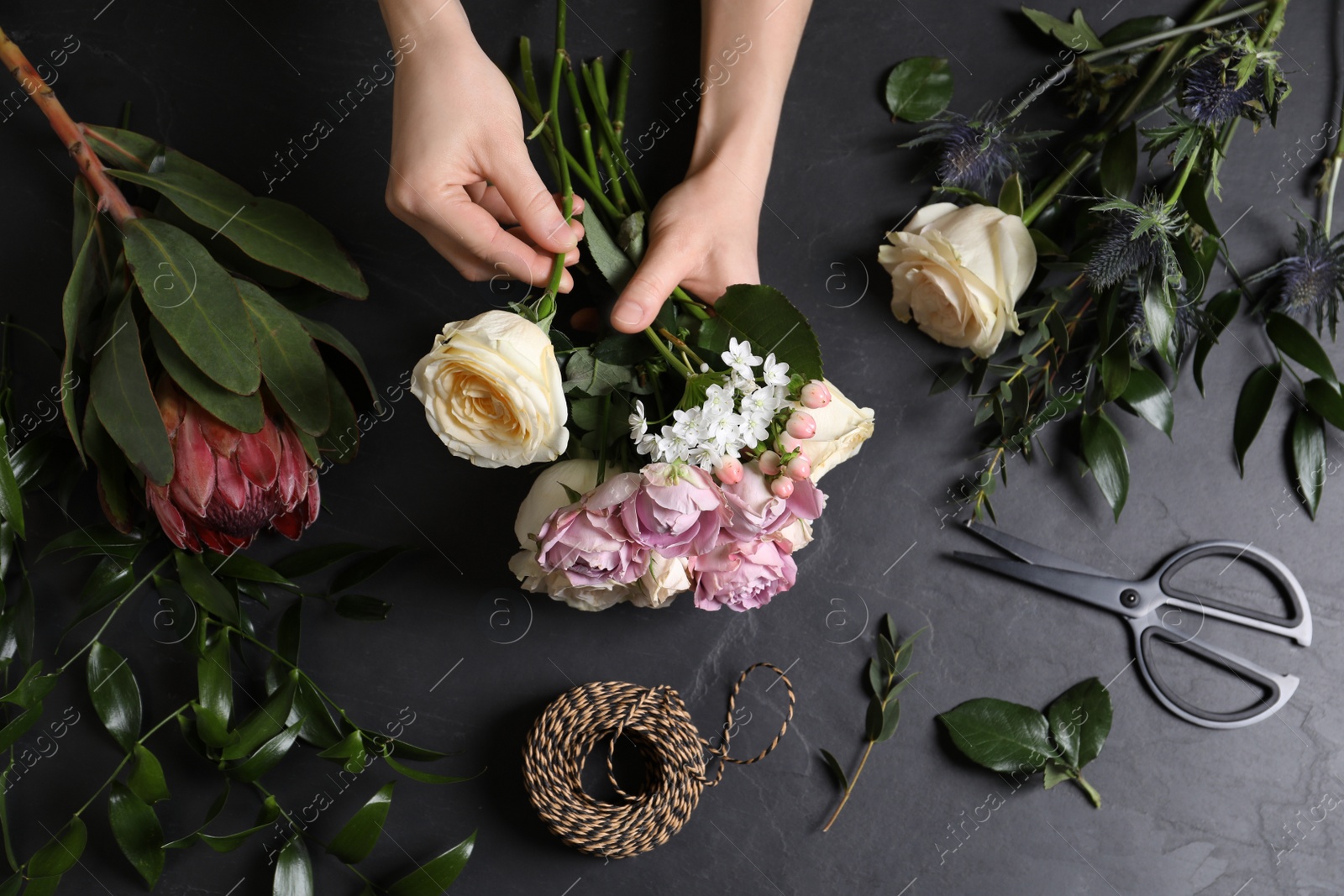 Photo of Florist making beautiful bouquet at black table, top view