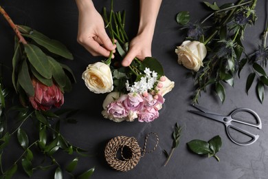 Photo of Florist making beautiful bouquet at black table, top view