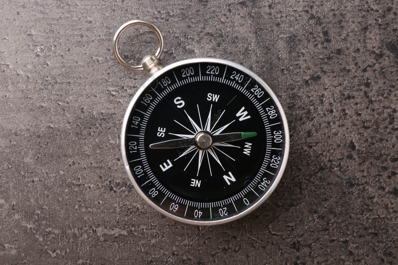 Photo of One compass on grey table, top view. Tourist equipment