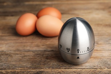 Photo of Kitchen timer and eggs on wooden table. Space for text