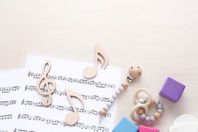 Wooden notes, music sheets and toys on beige background, flat lay with space for text. Baby song concept