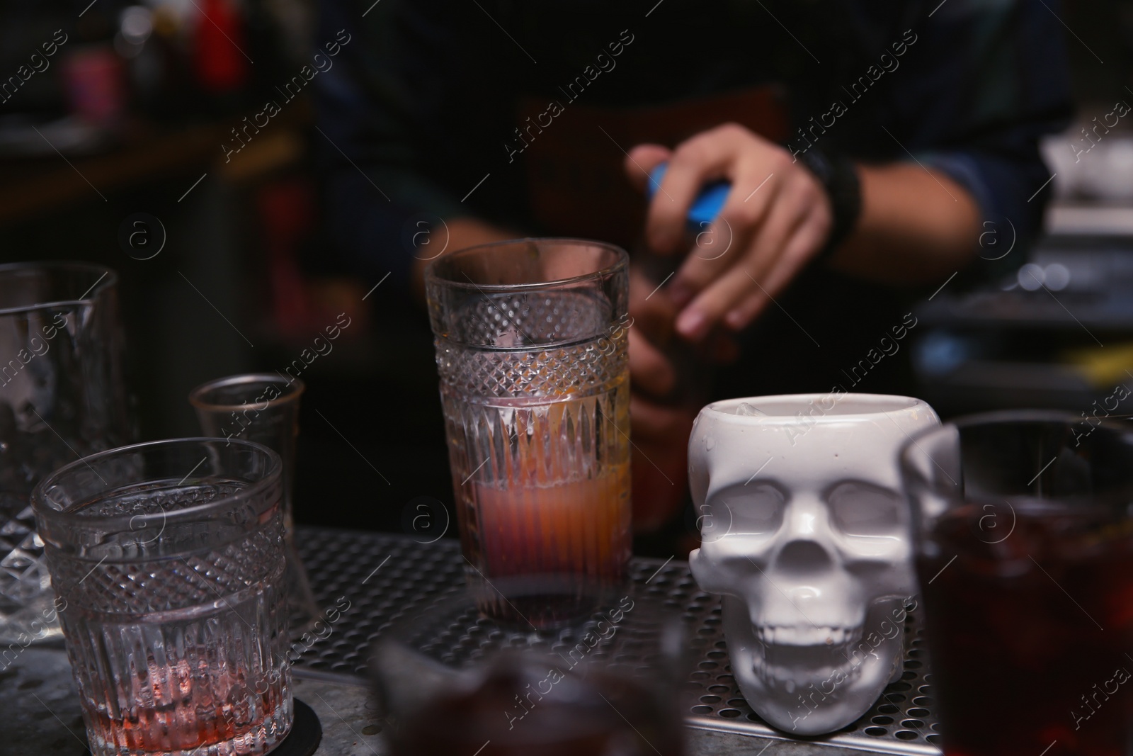 Photo of Glass of cocktail and skull cup on bar counter