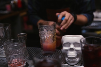 Photo of Glass of cocktail and skull cup on bar counter