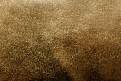 Photo of Shiny golden leather as background, top view