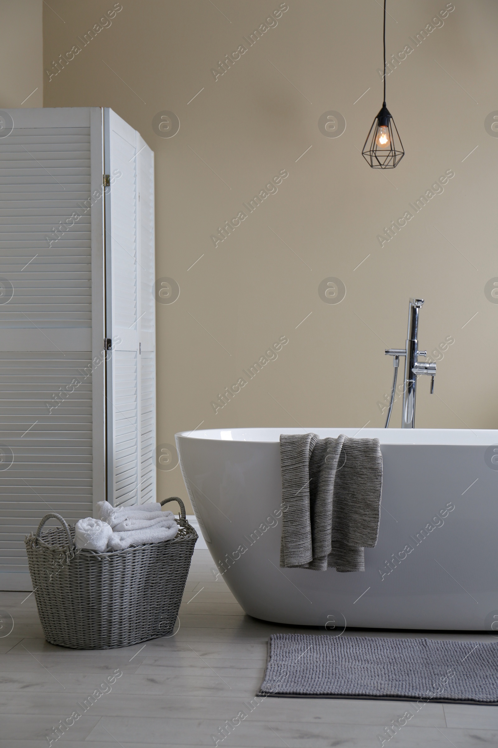 Photo of Soft grey mat on floor near tub in bathroom. Interior design