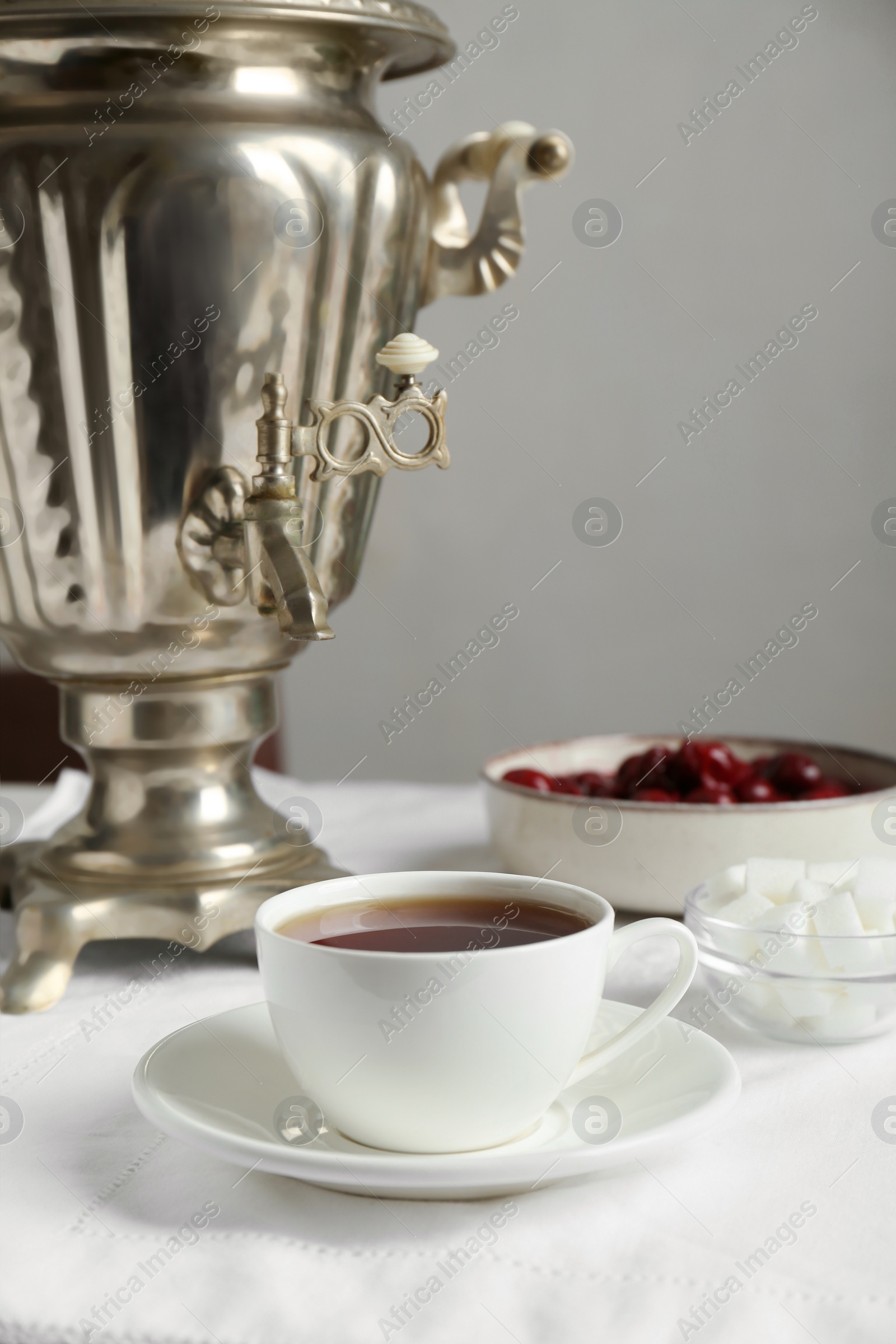 Photo of Vintage samovar, cup of hot drink and snacks served on table. Traditional Russian tea ceremony