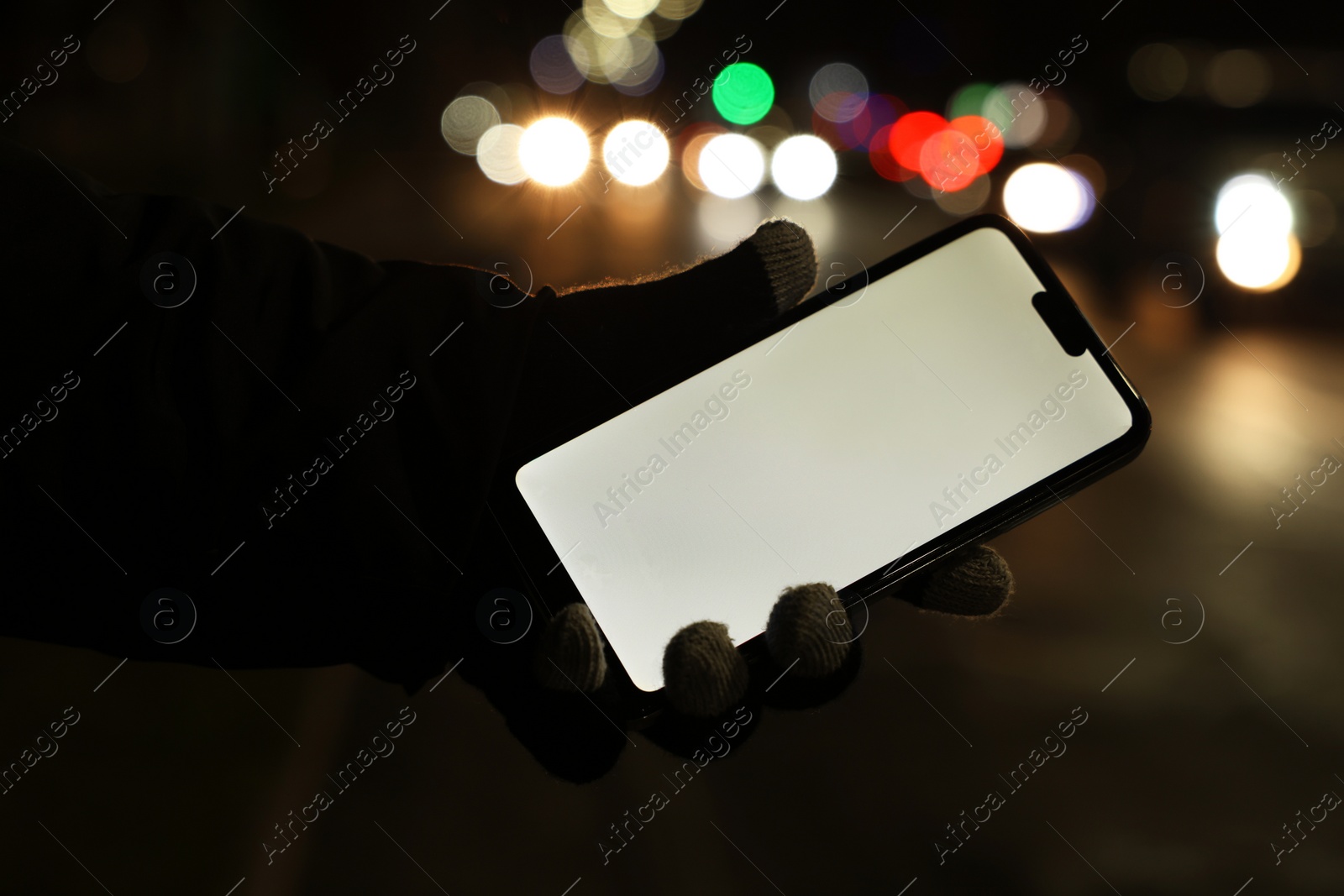 Photo of Man holding smartphone on night city street, closeup