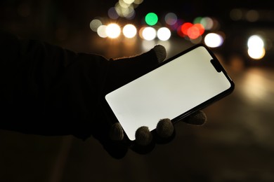 Photo of Man holding smartphone on night city street, closeup